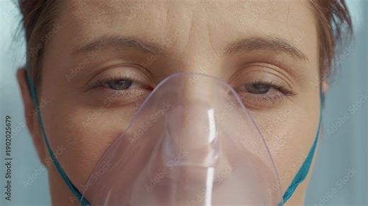 A woman inhales a saline solution through a mask to help treat her respiratory infection. She uses a nebulizer for cough relief and to manage pneumonia symptoms.