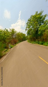 Fast FPV drone flight over the road in the middle of a summer forest on a sunny day.