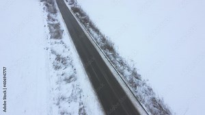 Asphalt road in a snowy field. Melted snow on the road, slush, slippery and dangerous.