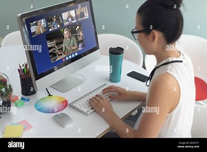 Asian businesswoman sitting at desk using computer having video call with group of colleagues. work at a modern office Stock Photo - Alamy