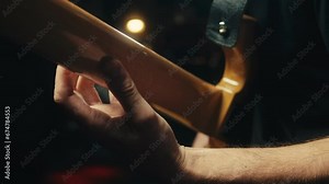 Young musician man sitting and playing the electric acoustic guitar among music equipment in studio close-up. Guitarist plays melody. Playing the chords. Solo concert, music repetition