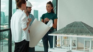 Professional architect engineer team talking, sharing, brainstorming about design while manager hold at project plan. Young architect holding plan while manager listen and point at plan. Tracery