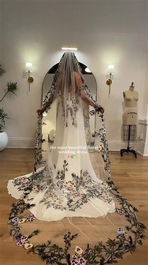 Meet our Eden dress 🌿 Adorned with a field of colorful yellow, purple, and blue embroidered pansies that fall delicately down the skirt. • • #weddingdresses #weddingdress #wedding #weddingdressshopping #uniqueweddingdress #BridalBoutique #2027bride #2026bride #cottagecore | Flora & Lane