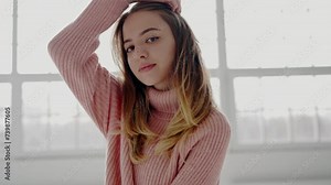 Beautiful woman in comfort warm sweater looking at camera. Portrait of young attractive female in pink sweater. Charming model posing in studio