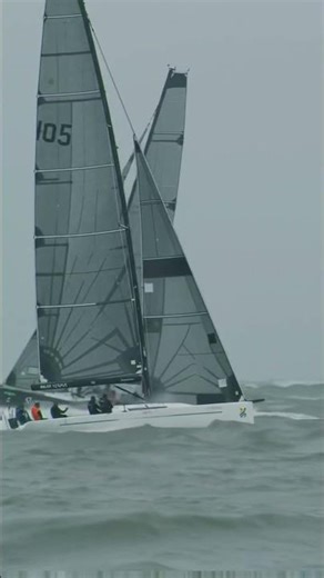 “Two sailboats race side by side through crashing waves and stormy winds.”