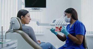 African american dentist demonstrates to patient how to properly brush teeth