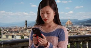 Lovely millennial woman using smart phone device to reply to text message in Florence Italy, Close up of young Asian tourist sending texts with cellphone near the Duomo, 4k