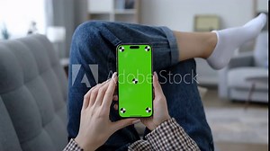 Woman using mobile phone vertical green screen. Female holding portable gadget close up indoors home living room. Mock-up for tracking. Browsing social network, news. Internet surfing. Tap on centre