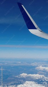 Airplane flying over colorado mountain ranges near aspen national forests snow covered usa close up wing view