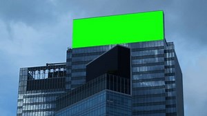 A large billboard with a green screen for advertising on the building wall.