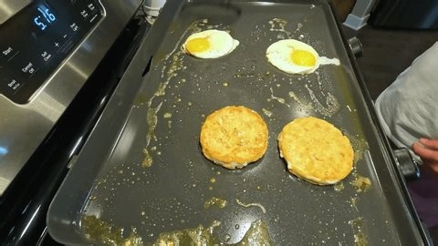 clip-3957325123-cooking-breakfast-eggs-sausage-patties-on-griddle