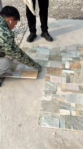 arranging various rectangular stone tiles into a pattern for floor installation at a construction
