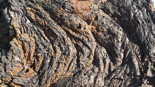 Solidified igneous lava rock shows porous basalt texture formed by rapid volcanic cooling. Rough stone surface reveals bubbles and hardened magma flow patterns in natural geology scene