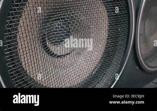 An audio speaker cone rests behind a protective black metal mesh grill. Shallow depth of field highlights the textured grid pattern. The detailed view showcases essential music studio equipment Stock Video Footage - Alamy