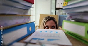 Businesswoman peeking out from under table with many folders and documents 4k movie slow motion