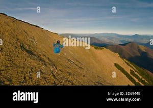 Breathtaking paragliding flight over colorful autumn mountains during a sunny evening. Experience peaceful, adrenaline-filled free flying and stunning aerial views with smooth follow camera motion.