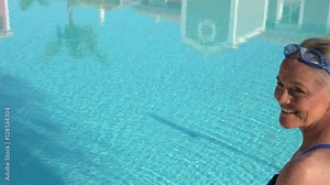 Reflections in swimming pool, camera pans to show woman by pool