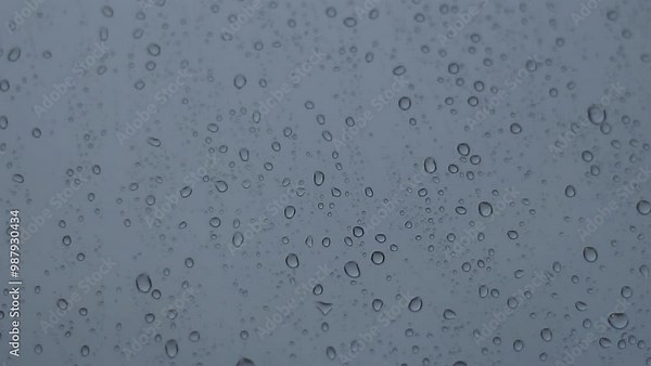 Heavy raindrops tapping on the window pane. Raindrops flowing down the window pane during a downpour. Rainy weather