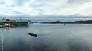 Time-lapse footage of Canadian geese swimming in a lake at sunrise with boathouse in the background