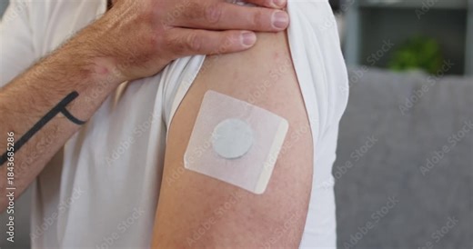 Man shows patch sensor for diabetes glucose. Wearable device on upper arm tracks levels, supporting health management and doctor-guided monitoring at home. Idea: home glucose monitor wearable.
