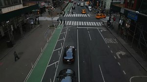 Backwards fly above street in metropolis. High angle view of cars on road, tilt up reveal of live street with traffic and pedestrians. New York City, USA in 2022