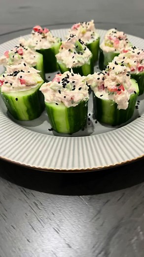 Tuna & Cucumber Bites Ingredients: * 1 English cucumber * 1 (5 oz) can of tuna, drained * 1/2 stalk celery, diced * 1/4 red bell pepper, diced * 1 small pickled cucumber, diced * 1/4 cup olives (green or black), sliced * 1/2 lemon * 1 tbsp mayonnaise * 1 tsp Dijon mustard * Black sesame seeds (for garnish) * Salt and pepper to taste Directions: 1. In a bowl, add the drained tuna. 2. Slice the cucumber into 2-inch pieces and hollow out the cores. 3. Dice the red bell pepper, celery, pickled cucum