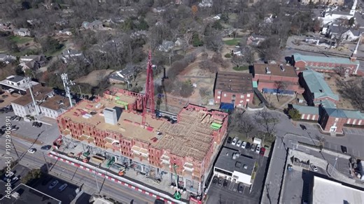 Large building under construction, aerial orbit shot circling a massive construction site with a multi-story structure in progress
