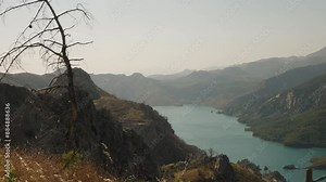 Expansive View of Turquoise Lake Winding Through Rugged Mountain Terrain, Emphasizing the Serene Beauty and Vastness of the Landscape.