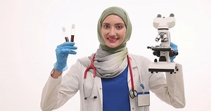 Muslim woman medic in hijab shows microscope and blood samples. Female medical professional demonstrates effective equipment for analysis
