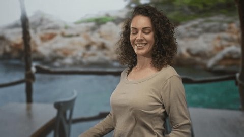 clip-3983624165-woman-smiling-standing-hands-on-table-by