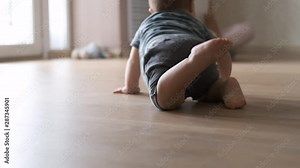 Baby boy crawling on floor at home in slow motion. Close-up of the baby's legs creeps to mother