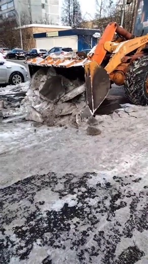 The front loader is scraping away the ice on the road.