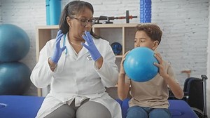 clip-3487207541-woman-therapist-conducts-rehab-exercise-young-boy