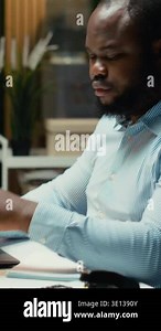 Vertical Video Black business expert engaged in handwriting notes for a presentation, extracting essential data from finance documents and making a summary with updates for business goals and tasks Stock Video Footage - Alamy