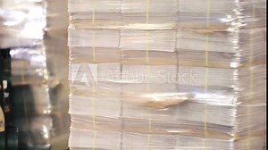 Wrapping newspapers with stretch at printing house for transportation. Rotating machine for packing at manufacture