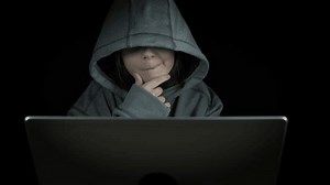 Child hacking on internet. A pensive child with computer addiction play games by her notebook against black background.