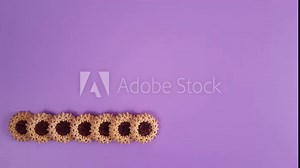 Stop motion animation with cookies. Round jam cookies appear one by one in a row at the bottom of a purple background. Repetitive video.