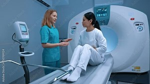Modern computed tomography room with professional radiologist doctor explaining process while standing close to patient. Computer tomography scanner, biopsy examination in diagnostic room at clinic.