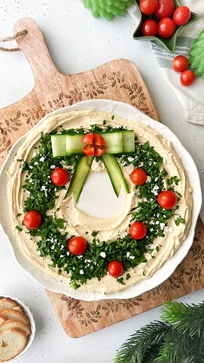 Kristel Talie on Instagram: "Snack like Santa with this festive ✨Hummus Wreath✨ It’s the easiest Christmas appetizer that looks as good as it tastes! You’ll need Hummus (I used around 500g) A handful of parsley finely chopped Cherry tomatoes Crumbled feta Cucumbers 1- Place a small bowl in the center of your plate and spread hummus evenly around it. 2- Remove the bowl, then top with parsley, tomatoes, and feta. 3- Peel cucumber strips with a veggie peeler, shape them into cute Christmas ribbons,