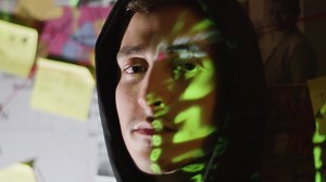 Young male hacker in hood looking at camera with binary code reflection on his face | Free Stock Video Footage