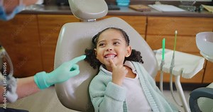 Pediatric dentist bonding with child, explaining dental procedure by making it fun or playful during consult. Friendly, adorable little girl learning about healthy teeth and maintaining oral hygiene