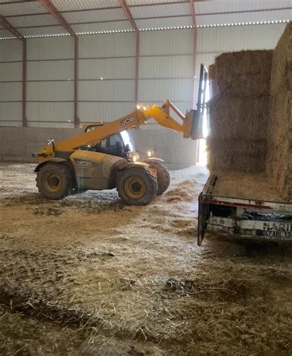 Yellow Forklift in Action: Lifting Hay Bales