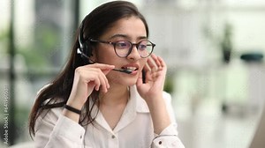 Beautiful young woman working with laptop and microphone in her office.