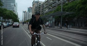 Young handsome man commute to work or school on minimalistic city bike. Student or office worker on way to university or office ride bike on bike lane. Pedalling and riding bike. Cycling in the city