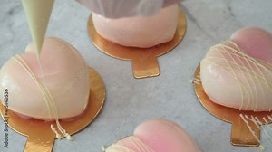 Professional pastry chef, decorating delicious dessert with a pastry bag, pour white glaze cake in the form of a heart on the kitchen table.