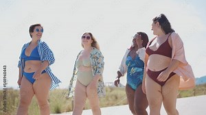 Cinematic storytelling footage of beautiful plus size women having fun at the beach in the summertime. Oversized big girls friends, representation of body positivity and body acceptance concepts