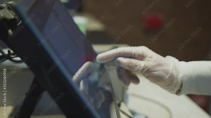 Close up of supermarket worker in protective gloves presses finger on computer screen. calculation of the cost of purchase in the supermarket