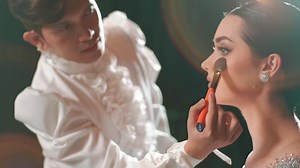 Makeup artist applying cosmetics to a model with a brush, focused and professional beauty session.