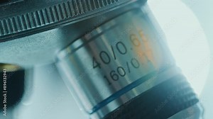 Microscope objective lens showing its specifications, including magnification of 40x and numerical aperture of 0.65 in medical laboratory. Macro view, tilt-up shot