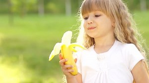 clip-2494457-girl-eating-banana-smiles-thumbs